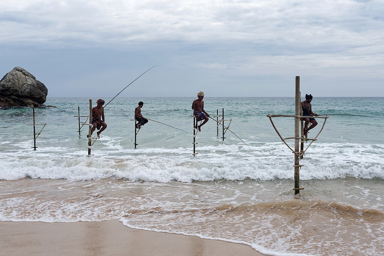 Fishermen sitting on wooden stilts in the surf near Galle, Sri Lanka